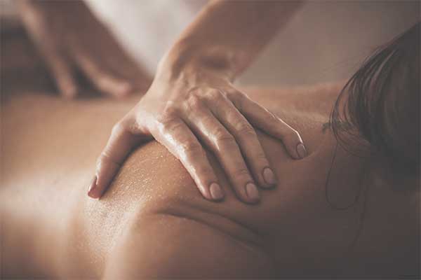 close-up of a hand massaging a woman's shoulder